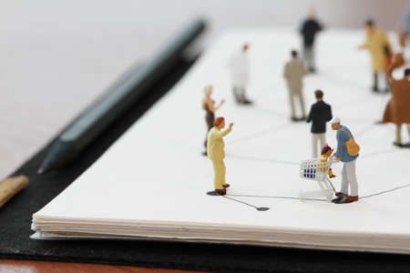 close up of miniature people with social network diagram on open notebook on wooden desk as social media conceptの写真素材