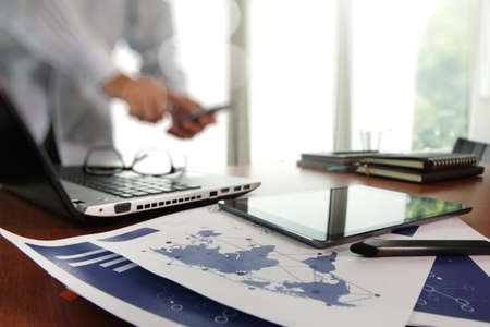 business documents on office table with smart phone and digital tablet and man working in the backgroundの写真素材