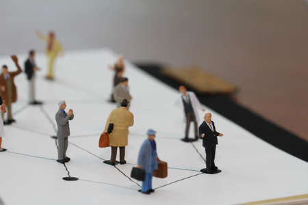 close up of miniature people with social network diagram on open notebook on wooden desk as social media conceptの写真素材