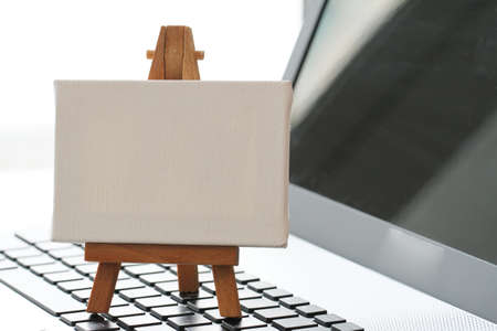 blank canvas and wooden easel on laptop computer as conceptの写真素材