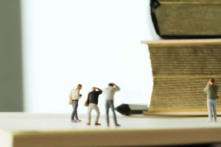Creative idea concept - miniature photographer with vintage golden book on open paper notebookの写真素材