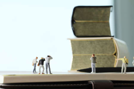 Creative idea concept - miniature photographer with vintage golden book on open paper notebookの写真素材