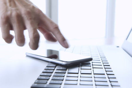 designer hand working and digital tablet and laptop on wooden desk in office