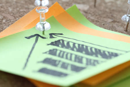 close up of pin and hand drawn business strategy graph chart on sticky note with cork board as conceptの写真素材