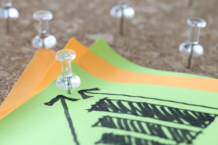 close up of pin and hand drawn business strategy graph chart on sticky note with cork board as conceptの写真素材