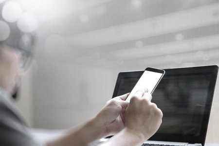 double exposure of young designer working with blank screen smart phone and computer in bed as conceptの写真素材