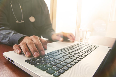 Doctor working with laptop computer in medical workspace office and overcast exposure effect