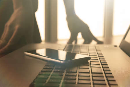 designer hand working and smart phone and laptop on wooden desk in officeの写真素材