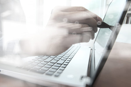 business man hand working with laptop computer and touching on screen on wooden desk as concept