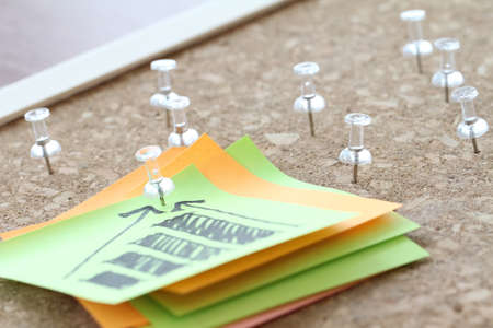 close up of pin and hand drawn business strategy graph chart on sticky note with cork board as conceptの写真素材