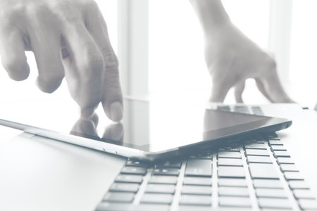designer hand working and digital tablet and laptop on wooden desk in officeの写真素材