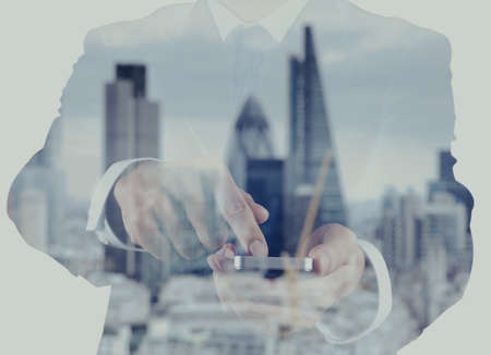 Double exposure of success businessman using smart phone with london city blurred backgroundの写真素材