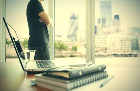 business documents on office table with smart phone and digital tablet and london city blurred view and man working in the backgroundの写真素材