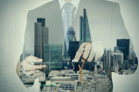 Double exposure of success businessman using digital tablet with london building and social media diagramの写真素材