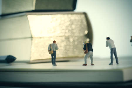 Creative idea concept - miniature photographer with vintage golden book on open paper notebookの写真素材