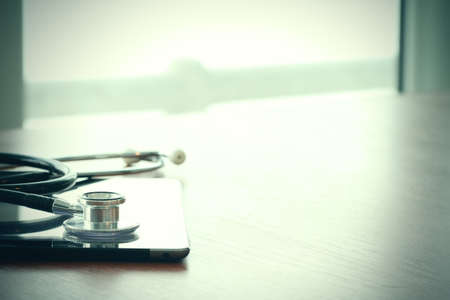 Studio macro of a stethoscope and digital tablet with shallow DOF evenly matched abstract on wood table background copy spaceの写真素材