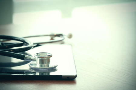 Studio macro of a stethoscope and digital tablet with shallow DOF evenly matched abstract on wood table background copy spaceの写真素材