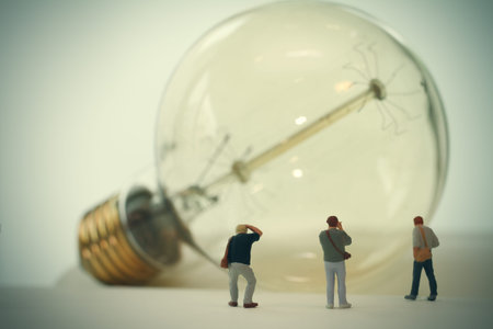 Creative idea concept - miniature photographer with vintage light bulb on open paper notebookの写真素材