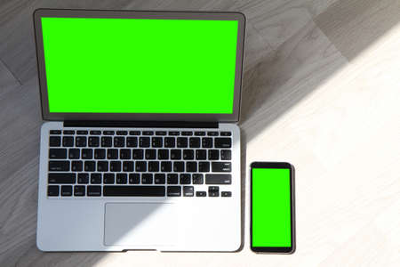 top view blank screen laptop computer and smart phone and digital tablet and stylus pen and mirror is on wooden desk as workplace conceptの写真素材