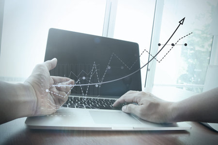 Close up of business man hand working on laptop computer with business graph information diagram on...