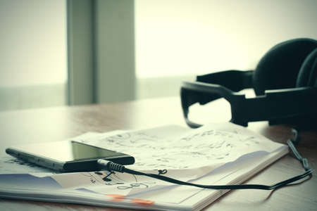 Composing music concept with shallow DOF evenly matched jack of headphone and crumpled musical notes paperの写真素材