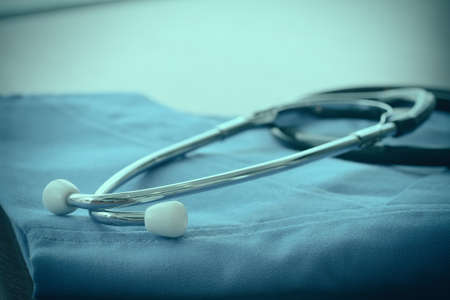 Stethoscope with blue doctor coat on wooden table with shallow DOF evenly matchedの写真素材