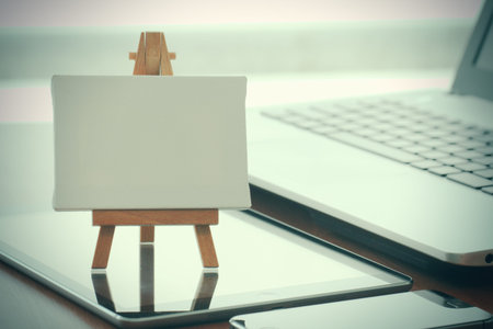 blank canvas and wooden easel on laptop computer as concept