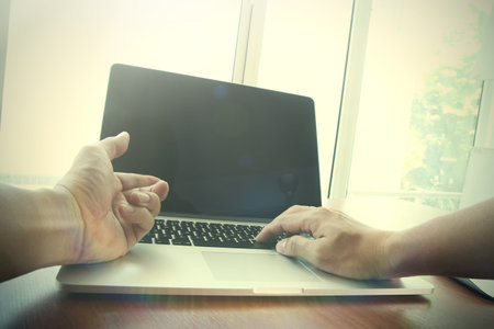 Close up of business man hand working on blank screen laptop computer on wooden desk as concept
