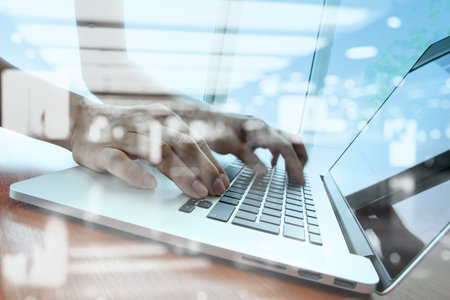 double exposure of businessman hand working with business documents on office table with laptop...