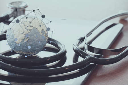 stethoscope and texture globe with digital tablet with social media network diagram as medical network conceptの写真素材