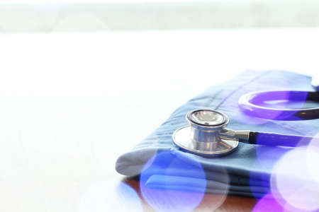 Stethoscope with blue doctor coat on wooden table with shallow DOF evenly matched and backgroundの写真素材