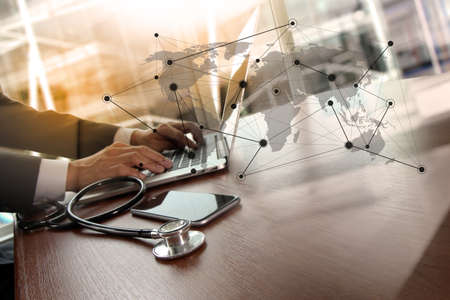 Doctor working at workspace with laptop computer in medical workspace office and medical network media diagram as conceptの写真素材