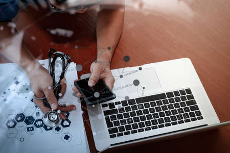 top view of Medicine doctor hand working with modern computer and smart phone with social media network on wooden desk as medical conceptの写真素材