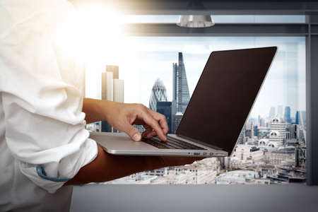 businessman working on his laptop in office with london city backgroundの写真素材