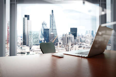 Office workplace with laptop and smart phone on wood table with london city background Office workplace with laptop and smart phone on wood table with london city background