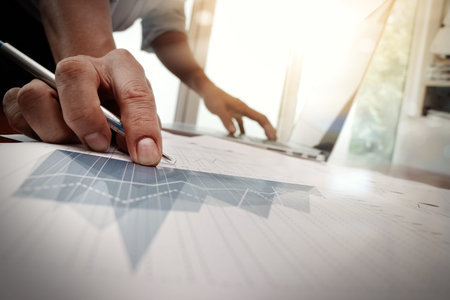 business documents on office table with smart phone and laptop computer and graph business with...
