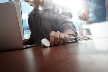 Medicine doctor hand working with modern computer and smart phone on wooden desk as medical conceptの写真素材