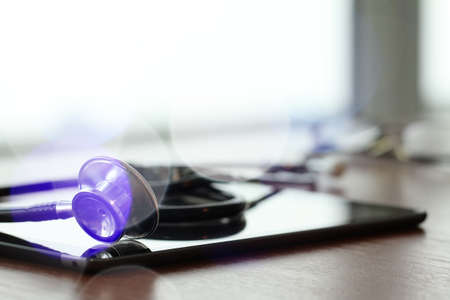 Studio macro of a stethoscope and digital tablet with shallow DOF evenly matched abstract on wood table background copy spaceの写真素材