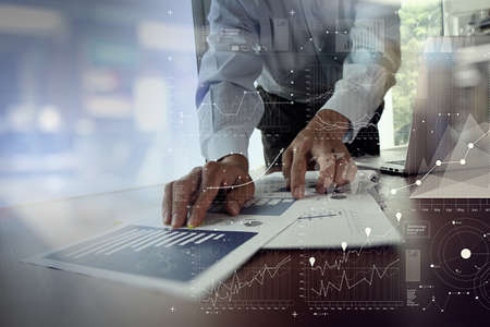 close up of business man hand working on laptop computer with business graph information diagram on wooden desk as concept