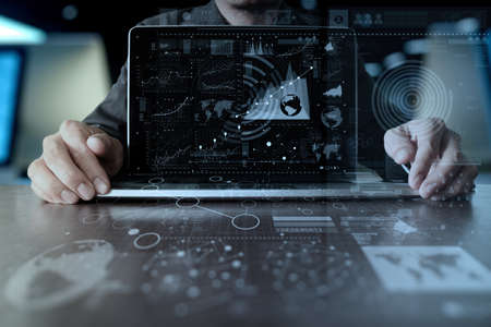 business man hand working on laptop computer with digital layer business strategy and social media diagram on wooden deskの写真素材
