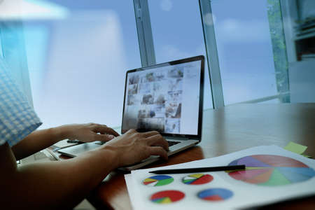 business documents on office table with smart phone and digital tablet and graph business diagram and man working in the backgroundの写真素材