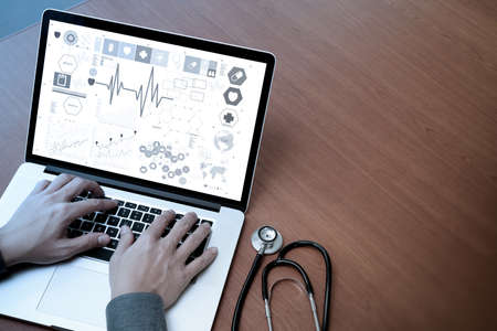 top view of Medicine doctor hand working with modern computer and digital medical layers on wooden desk as medical conceptの写真素材