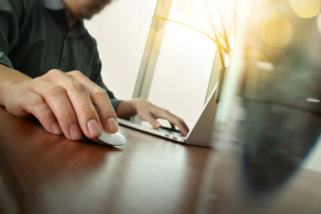 business man hand working on laptop computer with digital business strategy diagram on wooden desk...