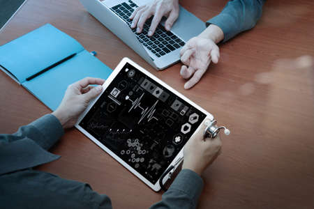 top view of Medicine doctor hand working with modern computer and digital pro tablet with digital medical diagram with his team on wooden desk as medical conceptの写真素材