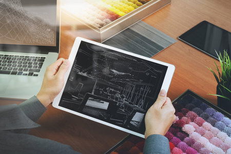 top view of Interior designer hand chosing carpet sample with blank new modern computer laptop and...