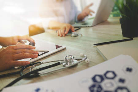 top view of Medicine doctor hand working with modern computer and digital pro tablet with blank screen with his team on wooden desk as medical conceptの写真素材