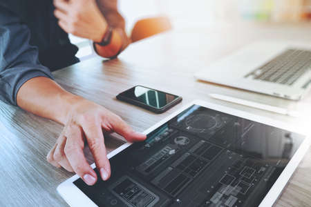 Website designer working digital tablet and computer laptop with smart phone and digital design diagram on wooden desk as concept