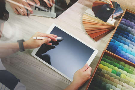 top view of two colleagues interior designers discussing data with digital tablet and new modern computer laptop with sample material on wooden desk as conceptの写真素材