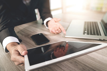 businessman working with blank screen digital tablet computer and smart phone and laptop computer on wooden desk as conceptの写真素材