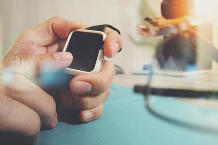 business presentation meeting on office table with smart watch and laptop computer and graph business diagram and three colleagues discussing data in the backgroundの写真素材